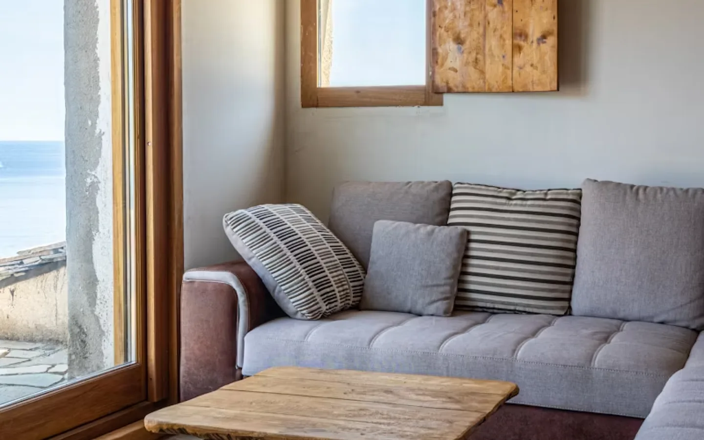 Salón con ventanal de carpintería de madera abierto al mar